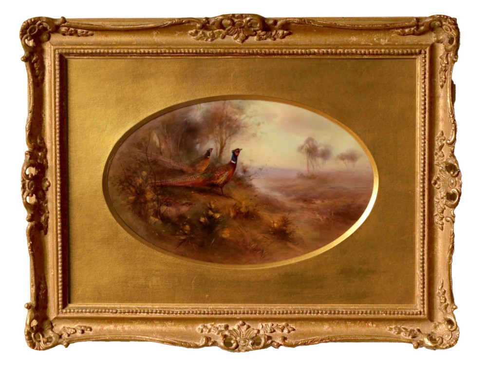 An oval-framed porcelain plaque featuring a hand-painted scene of two pheasants in a misty landscape, enclosed in a gold ornate frame.