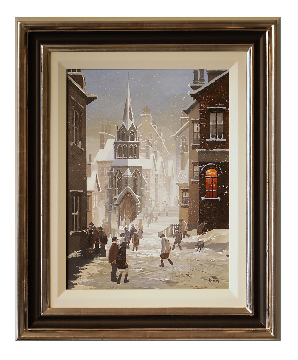 A framed oil painting on canvas depicting a snowy northern townscape with figures walking along a street lined with buildings leading towards a tall church spire.