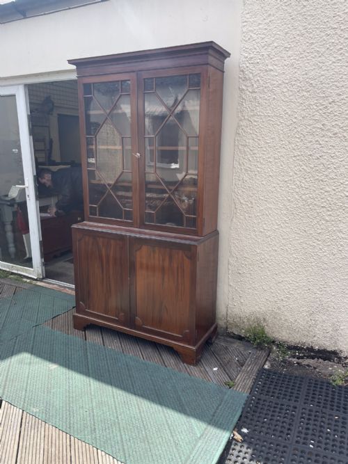 fig 1. An antique mahogany two-piece bookcase featuring an upper section with two astragal glazed doors and three internal shelves above a lower cabinet with two solid panelled doors.
