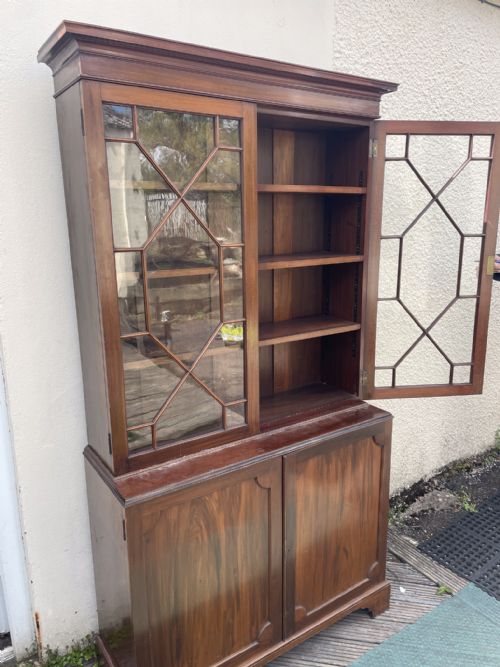 fig 2. An antique mahogany two-piece bookcase featuring an upper section with two astragal glazed doors and three internal shelves above a lower cabinet with two solid panelled doors.