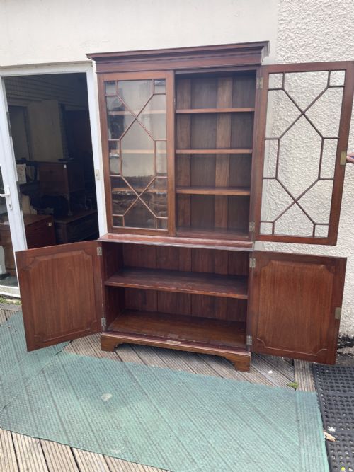 fig 3. An antique mahogany two-piece bookcase featuring an upper section with two astragal glazed doors and three internal shelves above a lower cabinet with two solid panelled doors.