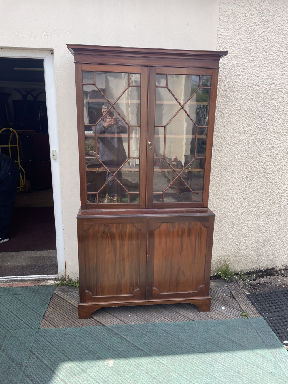 An antique mahogany two-piece bookcase featuring an upper section with two astragal glazed doors and three internal shelves above a lower cabinet with two solid panelled doors.