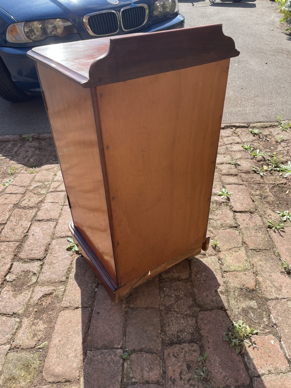 A Victorian mahogany bedside cabinet featuring a single panelled door with flame mahogany grain, a small turned knob, a plinth base, and a low gallery upstand. View IX