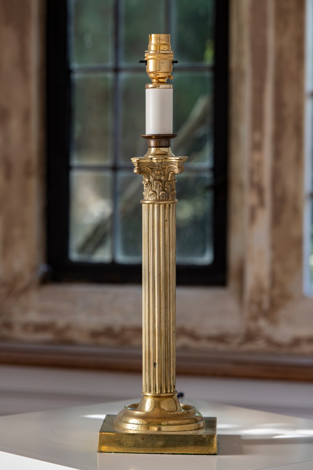 A nineteenth-century brass table lamp featuring a fluted column, classical capital, and square stepped base.