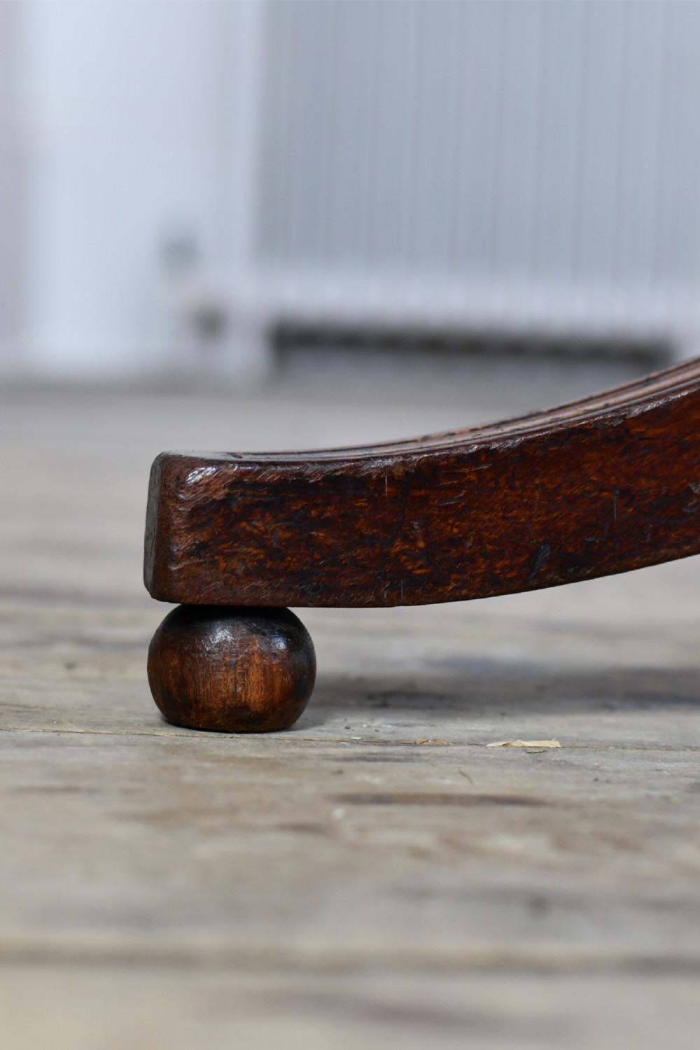 A Regency period mahogany tripod table featuring a square top with rounded corners, a central turned column, and three swept sabre legs. View III