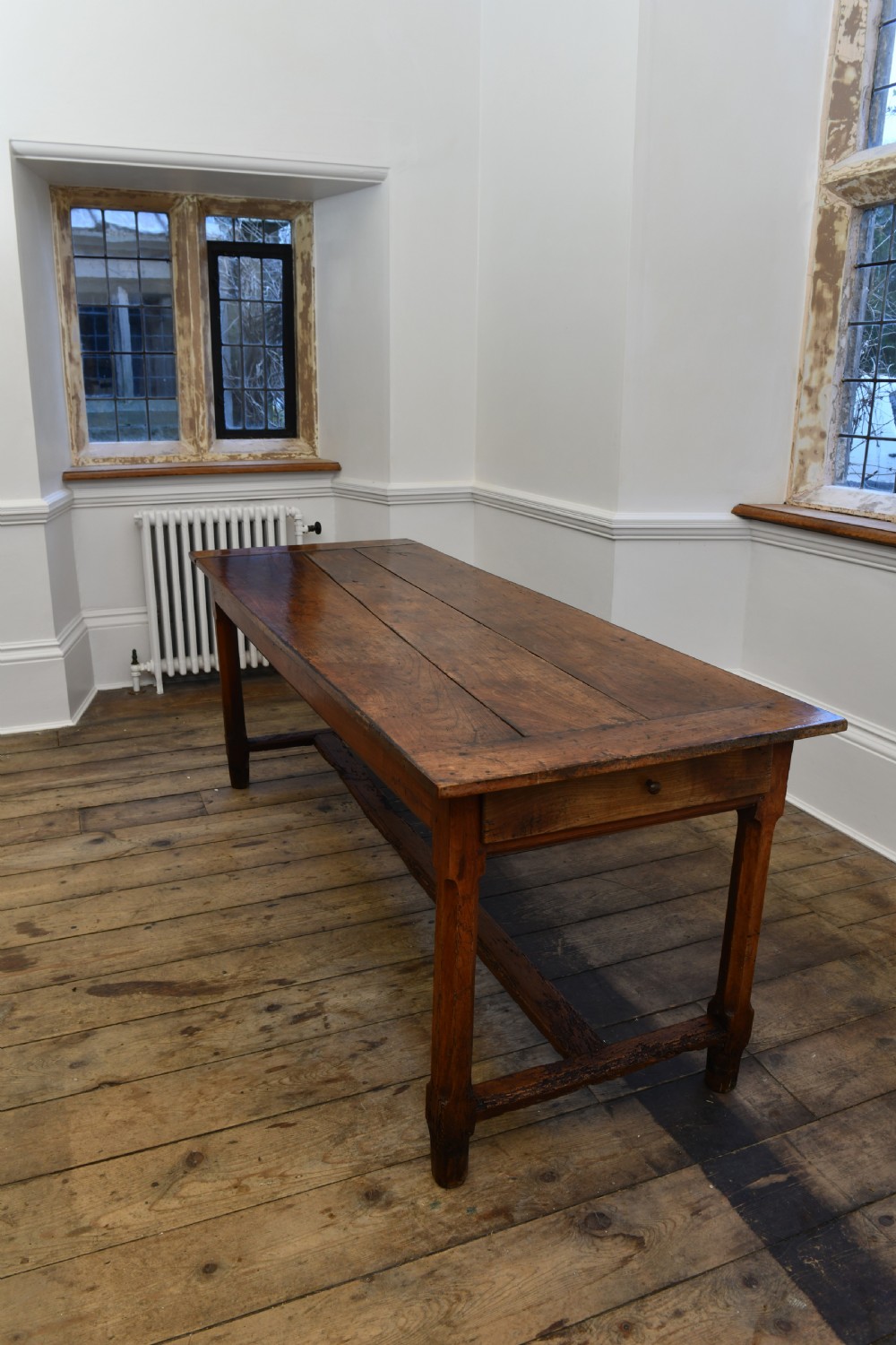 A long 19th-century rustic elm kitchen table featuring a plank top, a small end drawer, square legs, and a sturdy stretcher base. View II