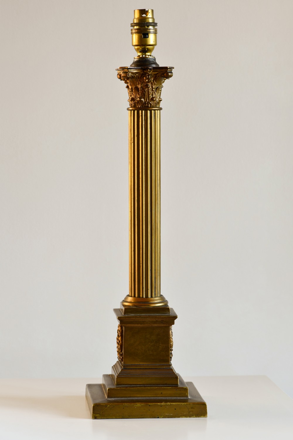 A late nineteenth-century brass table lamp featuring a fluted Corinthian column on a square stepped pedestal base.
