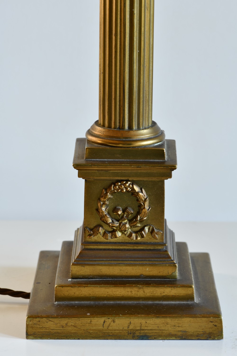 A late nineteenth-century brass table lamp featuring a fluted Corinthian column on a square stepped pedestal base. View VI