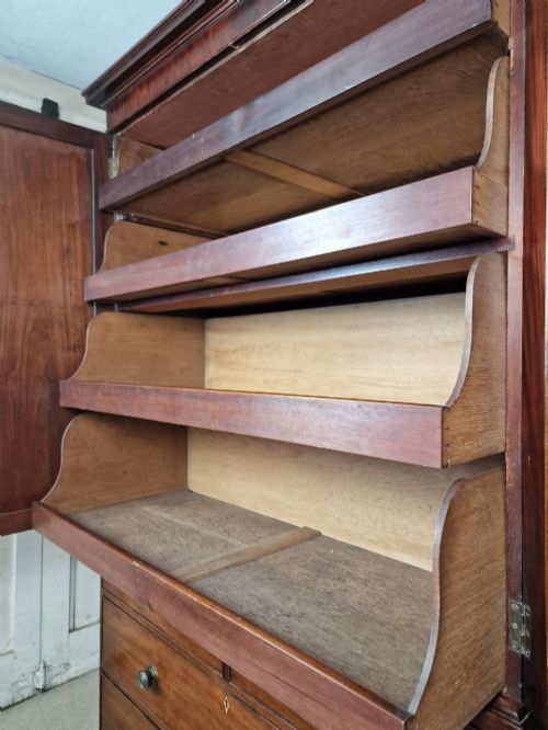 fig 1. An early nineteenth-century George IV flame mahogany linen press featuring a double-door upper cupboard over a chest of drawers with bracket feet.