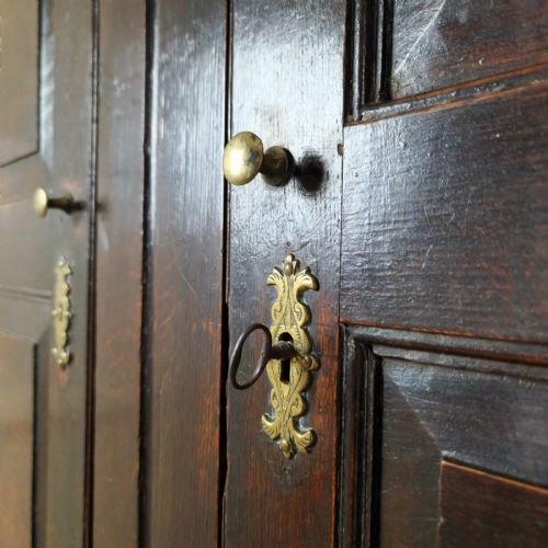 fig 1. A mid-18th-century dark oak Georgian livery cupboard featuring raised panel doors, brass fittings, and lower drawers.