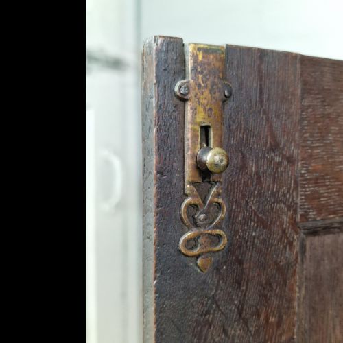 A late 18th-century Georgian oak wall cabinet featuring twin fielded panel doors, brass knobs, an escutcheon, and a moulded top cornice. View II