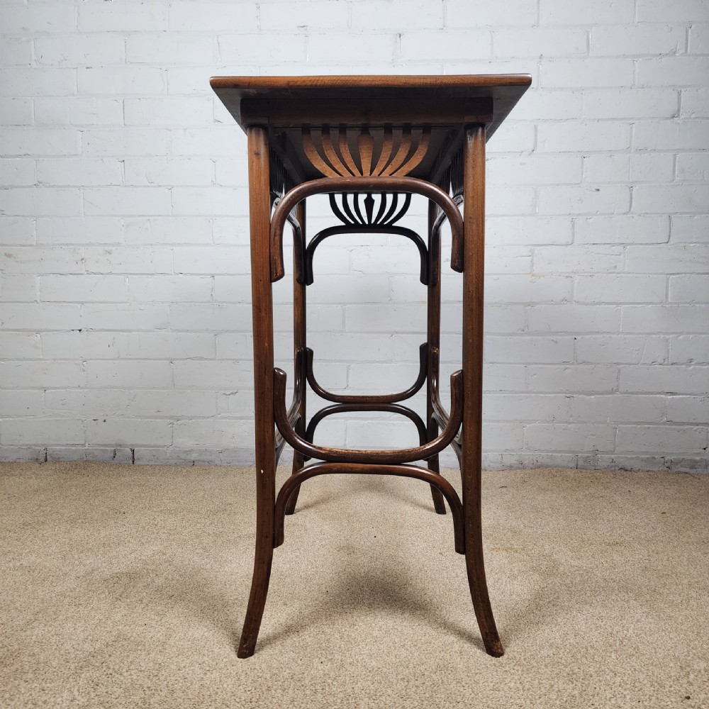 An Art Nouveau dark brown bentwood side table featuring carved palmette apron details and curved leg supports. View III