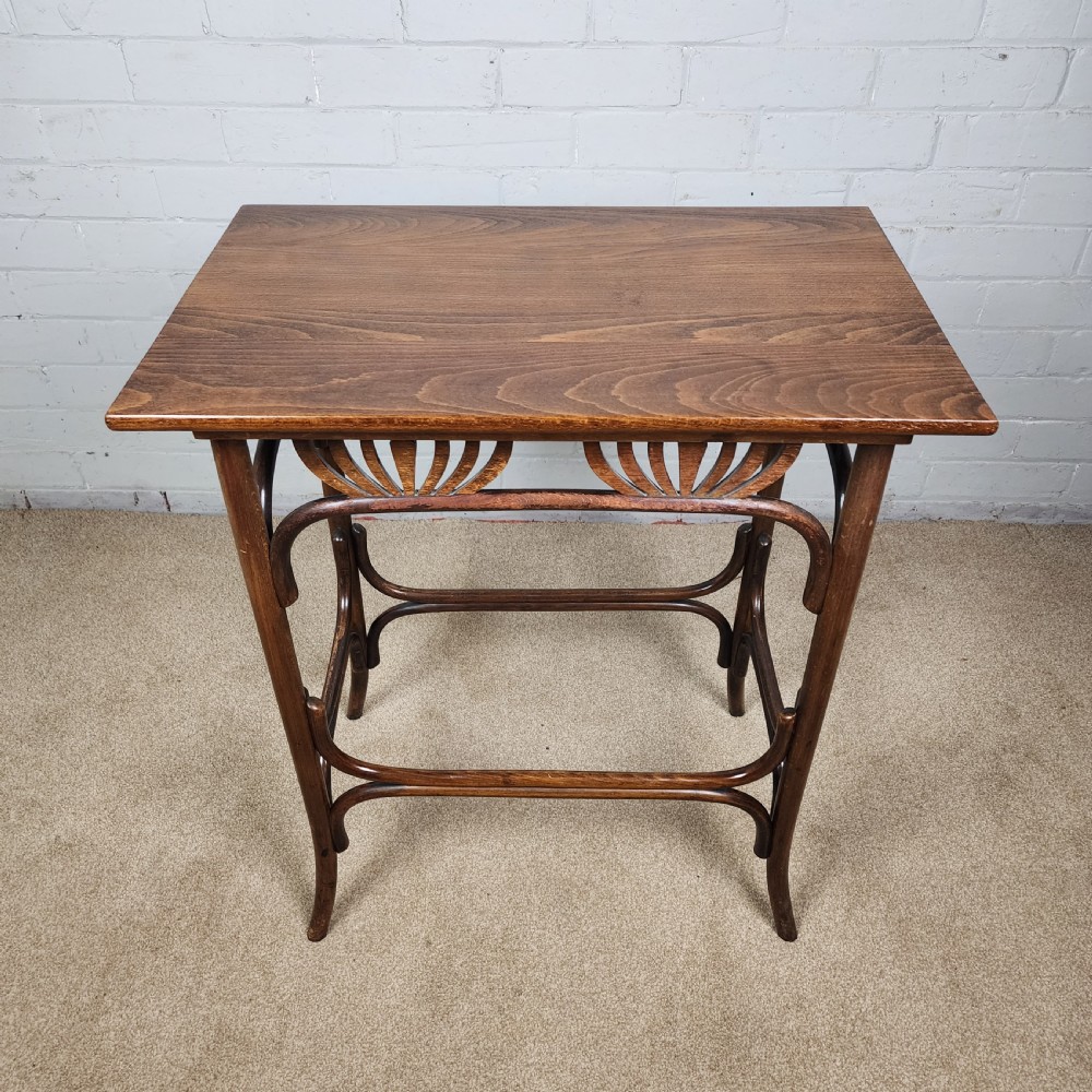 An Art Nouveau dark brown bentwood side table featuring carved palmette apron details and curved leg supports. View VII