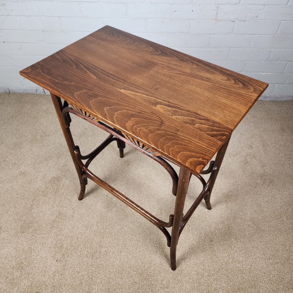 An Art Nouveau dark brown bentwood side table featuring carved palmette apron details and curved leg supports. View IX