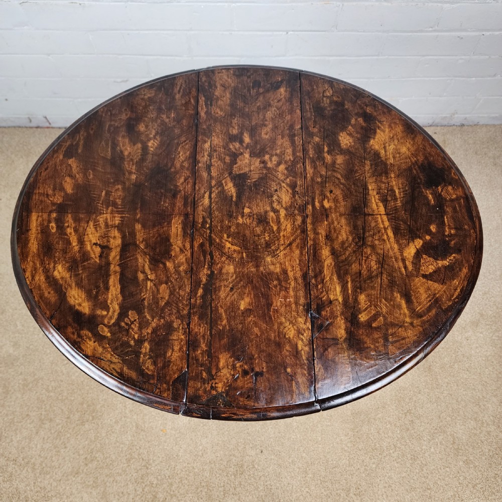 A Victorian circular occasional table made from dark burr walnut and mahogany, featuring drop leaves, a swivel top, a spiral carved central stem, and tripod carved feet. View II