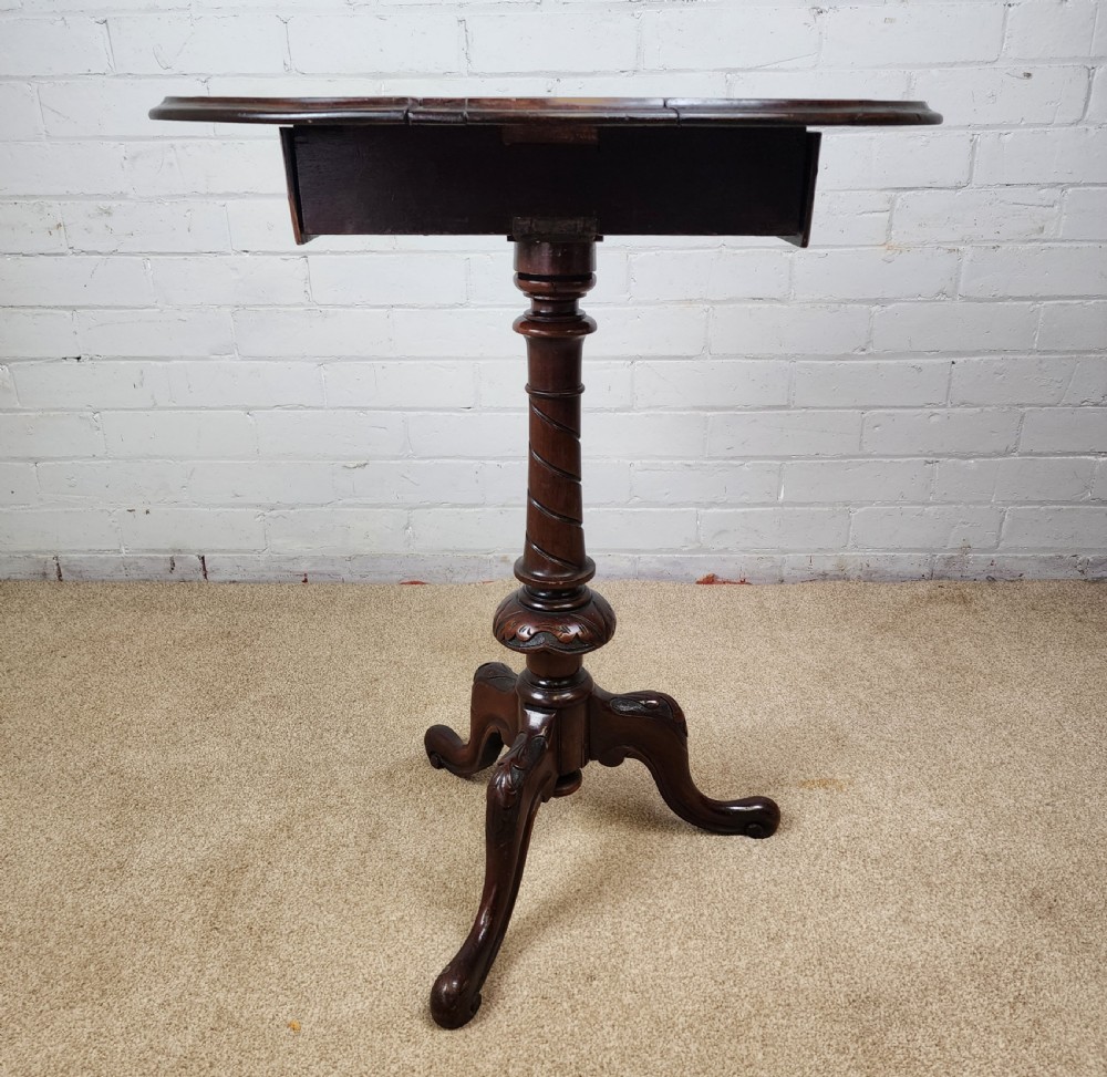 A Victorian circular occasional table made from dark burr walnut and mahogany, featuring drop leaves, a swivel top, a spiral carved central stem, and tripod carved feet. View III