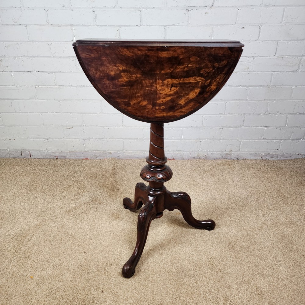 A Victorian circular occasional table made from dark burr walnut and mahogany, featuring drop leaves, a swivel top, a spiral carved central stem, and tripod carved feet. View VI