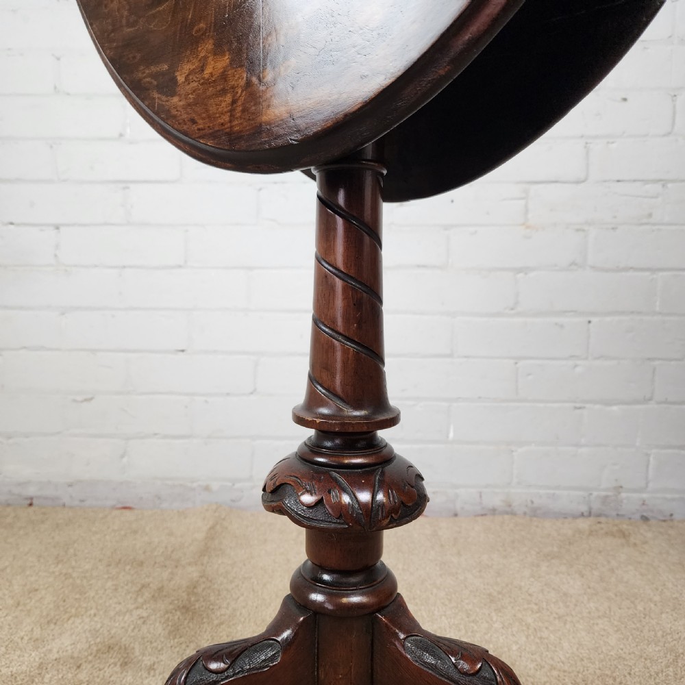 A Victorian circular occasional table made from dark burr walnut and mahogany, featuring drop leaves, a swivel top, a spiral carved central stem, and tripod carved feet. View VII