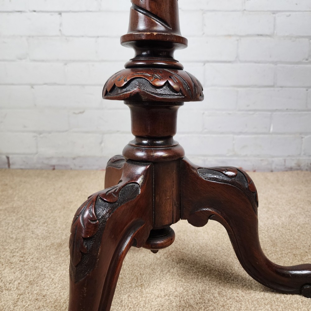 A Victorian circular occasional table made from dark burr walnut and mahogany, featuring drop leaves, a swivel top, a spiral carved central stem, and tripod carved feet. View IX