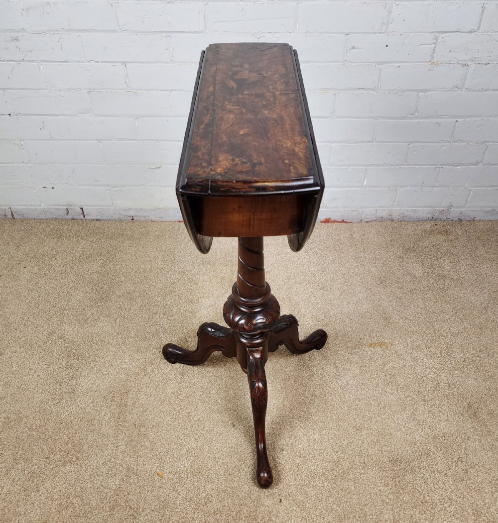 A Victorian circular occasional table made from dark burr walnut and mahogany, featuring drop leaves, a swivel top, a spiral carved central stem, and tripod carved feet. View X