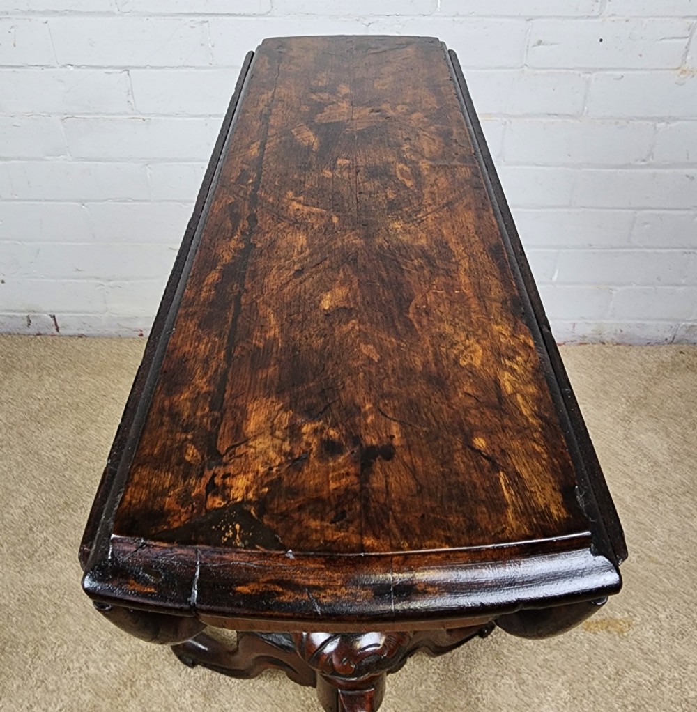 A Victorian circular occasional table made from dark burr walnut and mahogany, featuring drop leaves, a swivel top, a spiral carved central stem, and tripod carved feet. View XI