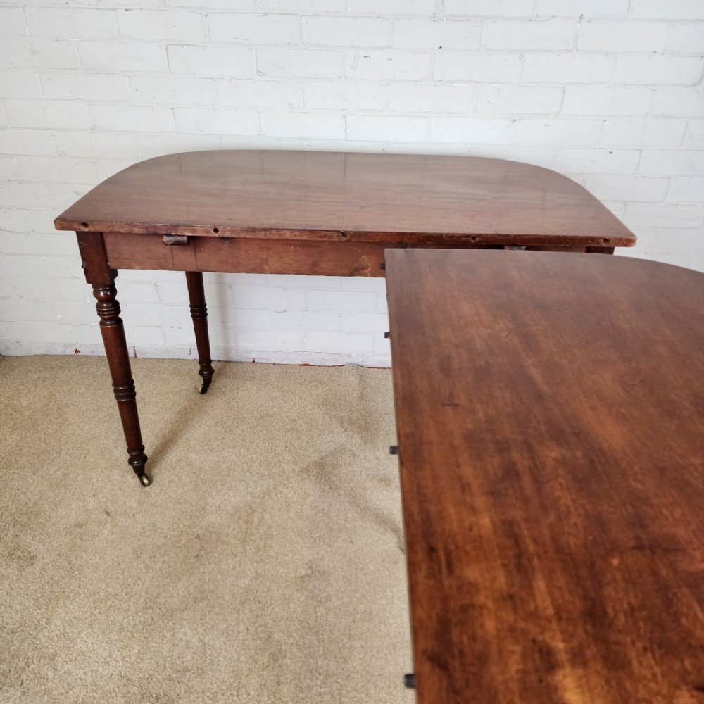 A George IV mahogany extending dining table featuring rounded D-ends, a polished timber surface, and turned legs. View II