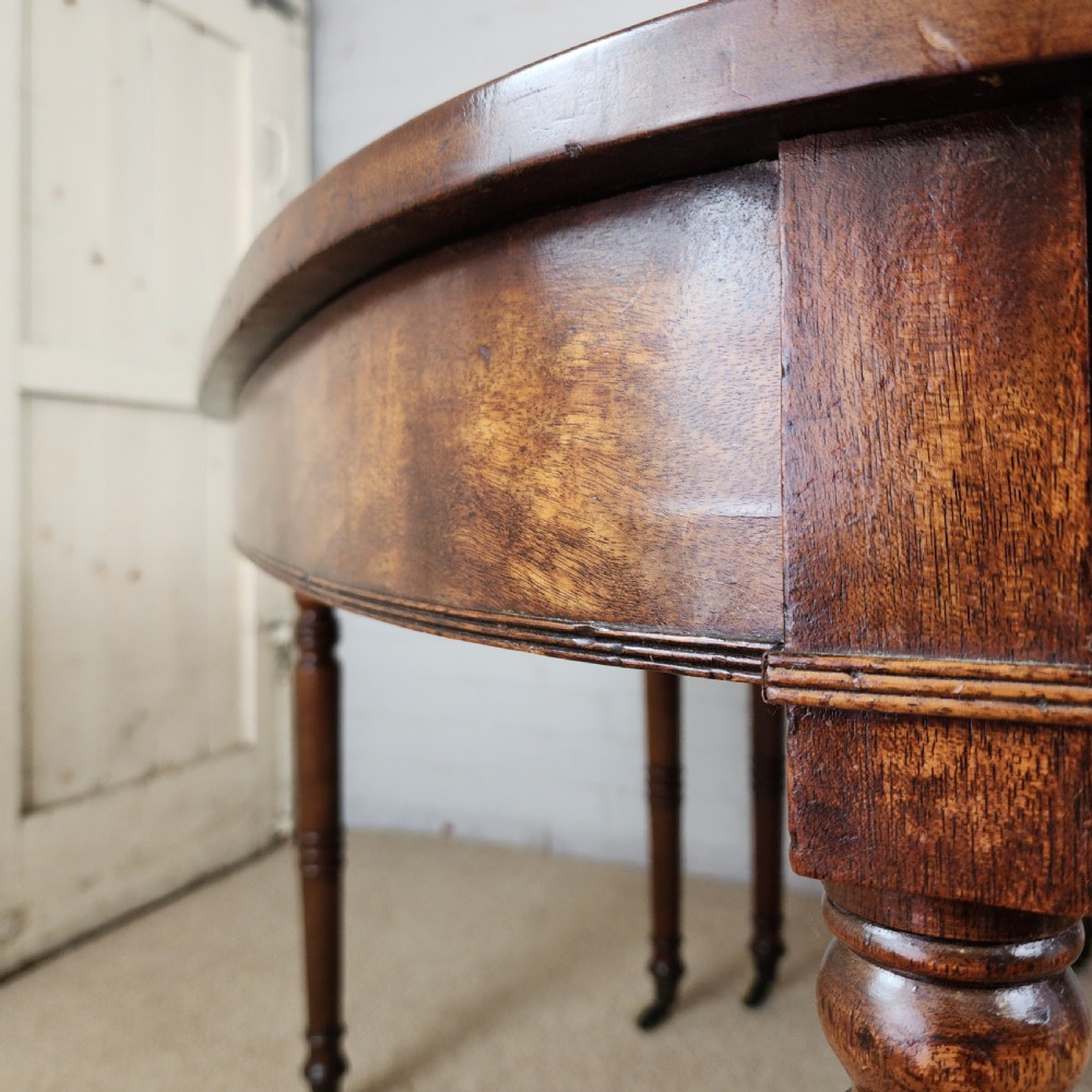 A George IV mahogany extending dining table featuring rounded D-ends, a polished timber surface, and turned legs. View VI