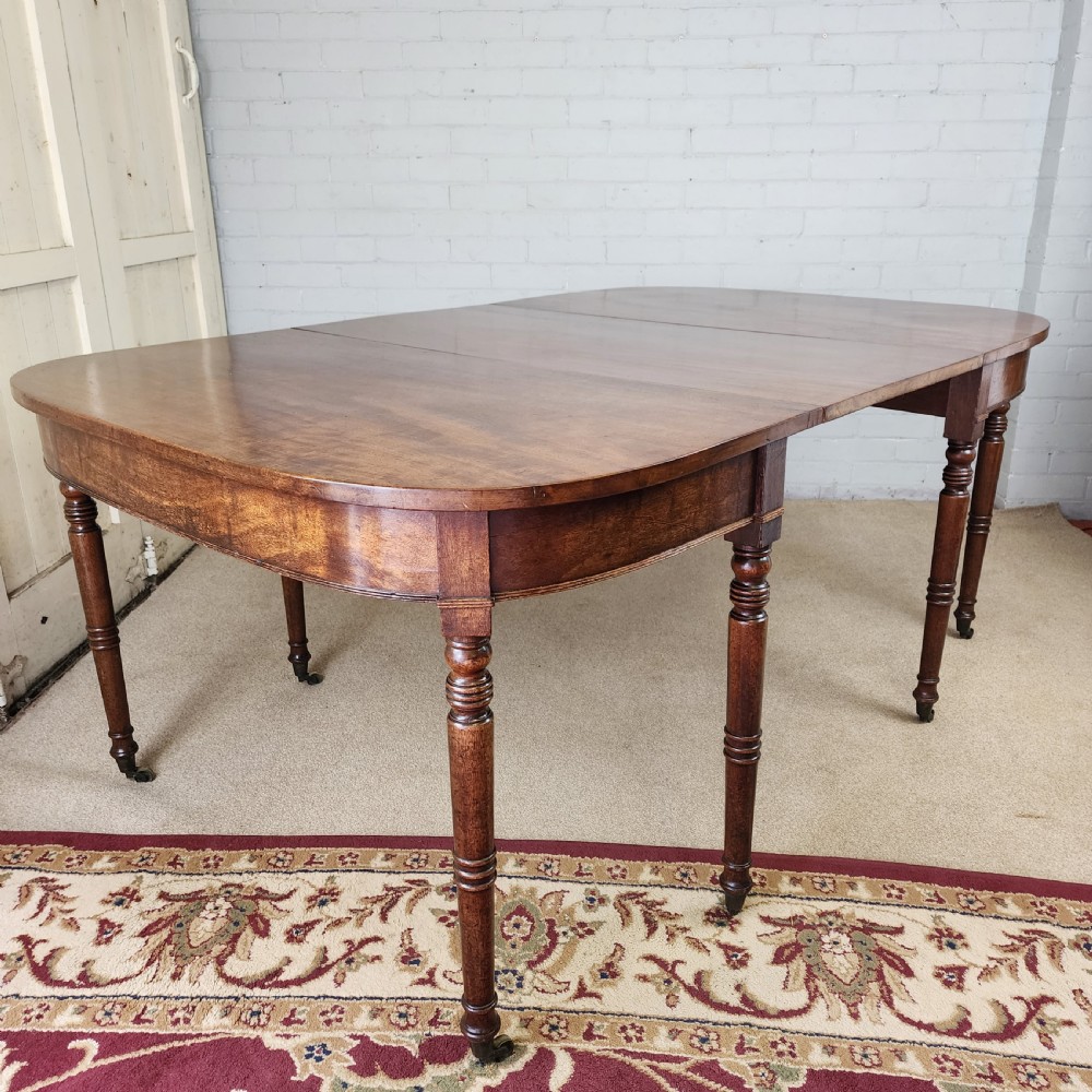 A George IV mahogany extending dining table featuring rounded D-ends, a polished timber surface, and turned legs. View X