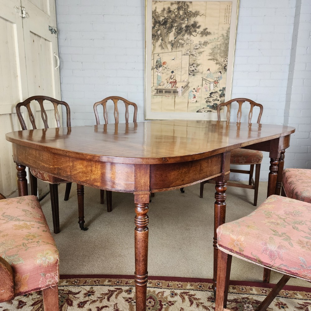 A George IV mahogany extending dining table featuring rounded D-ends, a polished timber surface, and turned legs. View XII