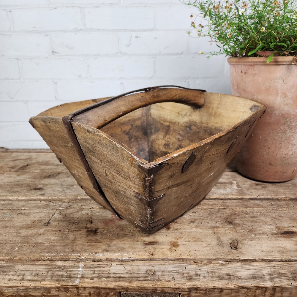 A nineteenth-century wooden garden trug featuring iron rim strapping, metal corner reinforcements, and a carved central carrying handle.