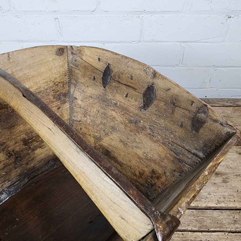 A nineteenth-century wooden garden trug featuring iron rim strapping, metal corner reinforcements, and a carved central carrying handle. View V