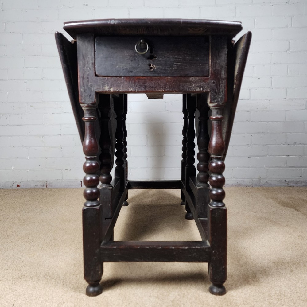A late seventeenth-century dark oak gateleg dining table with turned legs and two drop leaves extended. View X