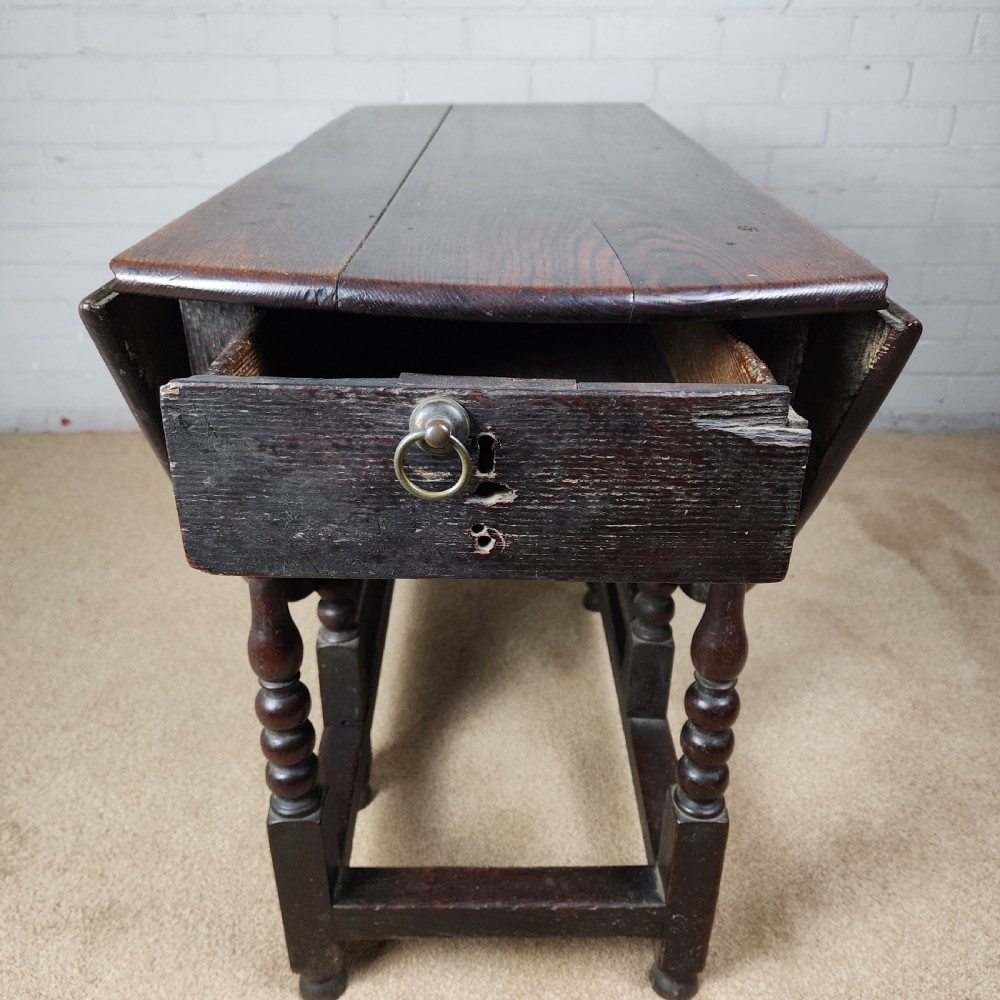 A late seventeenth-century dark oak gateleg dining table with turned legs and two drop leaves extended. View II