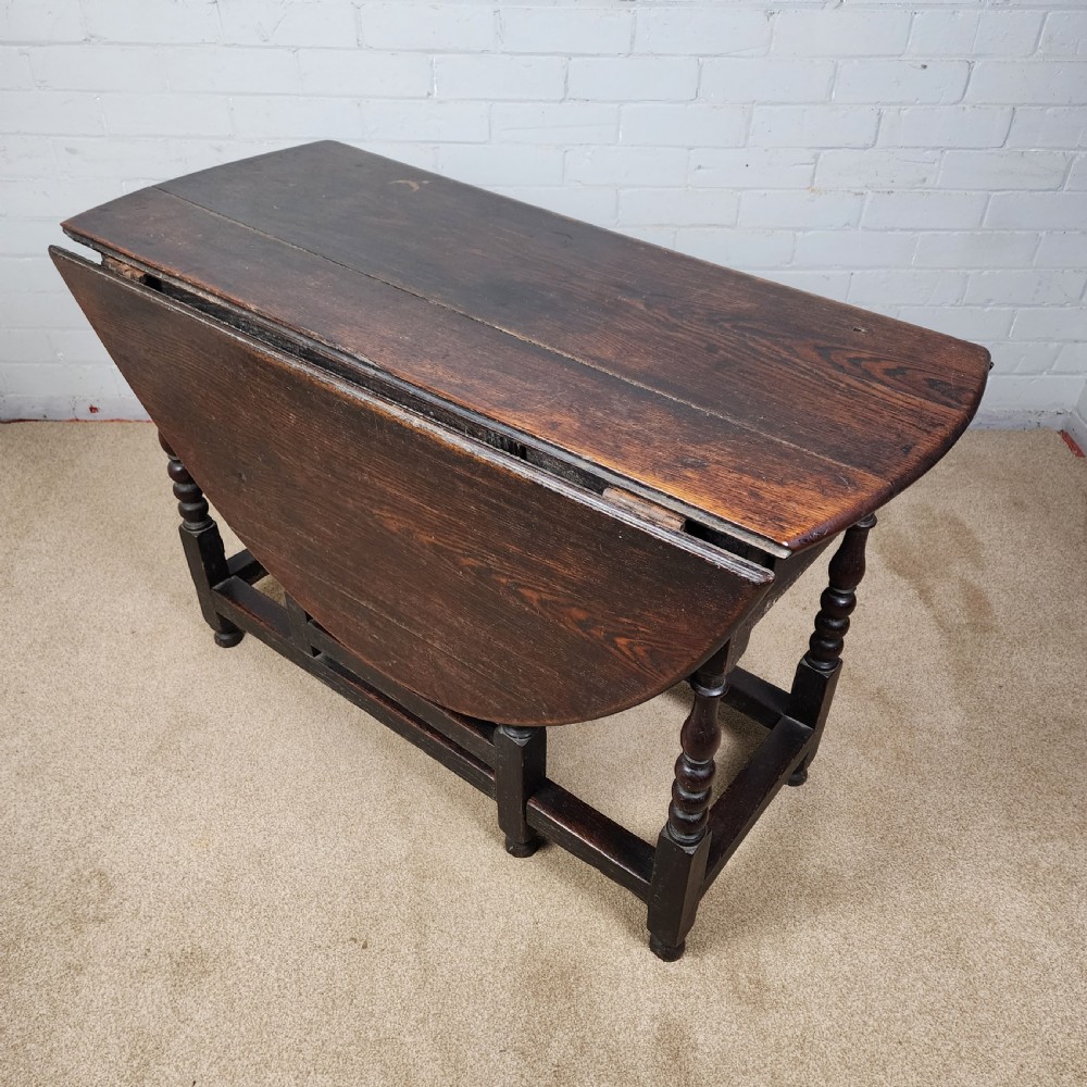 A late seventeenth-century dark oak gateleg dining table with turned legs and two drop leaves extended. View V