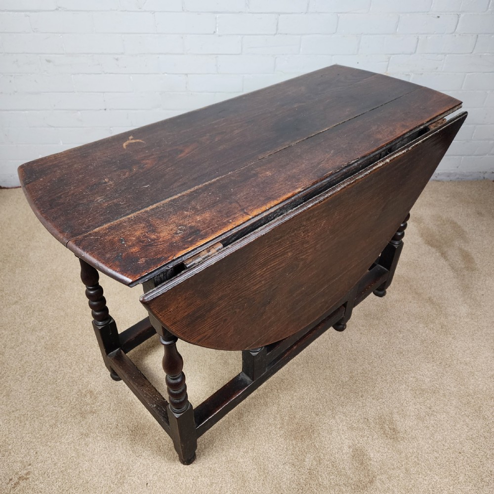 A late seventeenth-century dark oak gateleg dining table with turned legs and two drop leaves extended. View VI