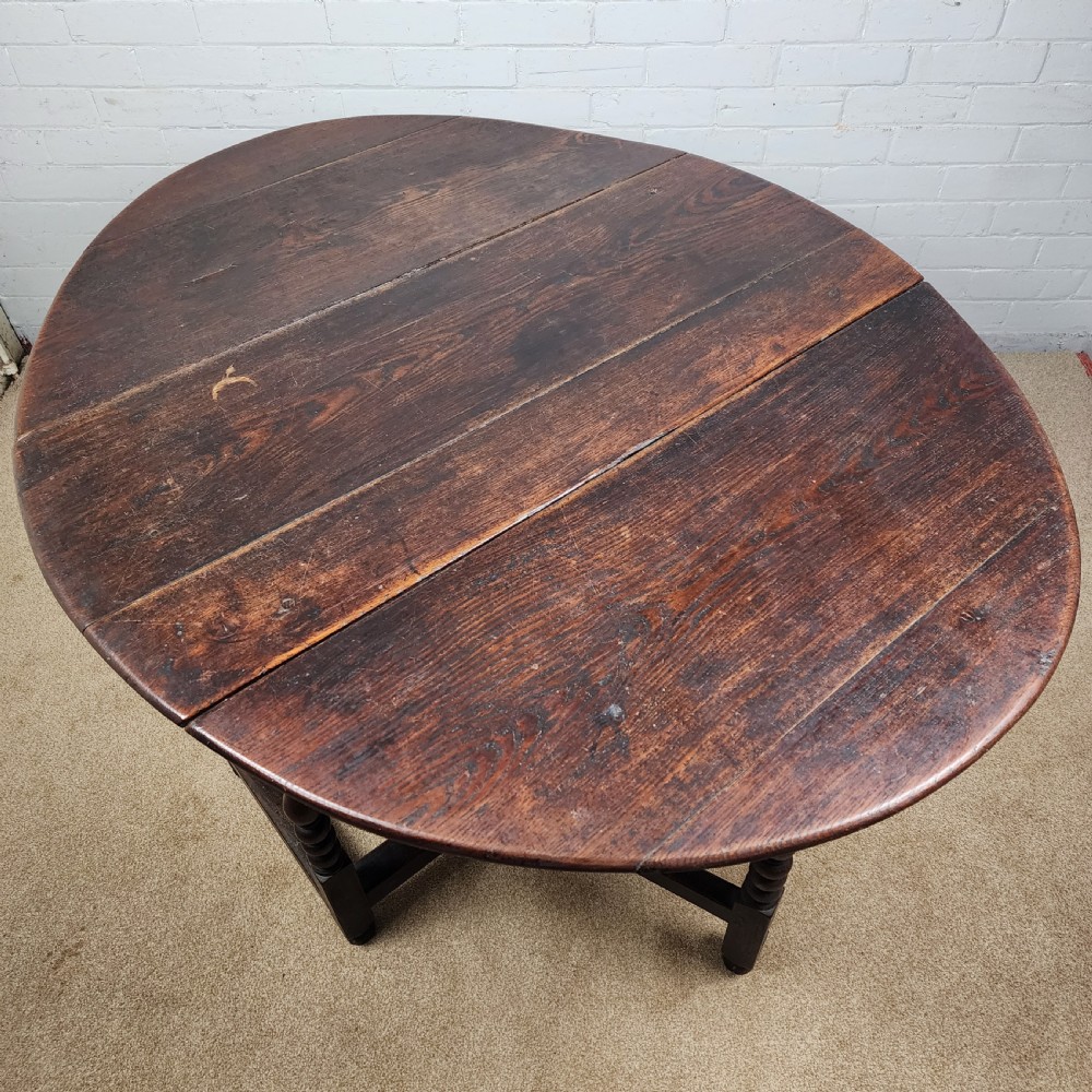A late seventeenth-century dark oak gateleg dining table with turned legs and two drop leaves extended. View VII