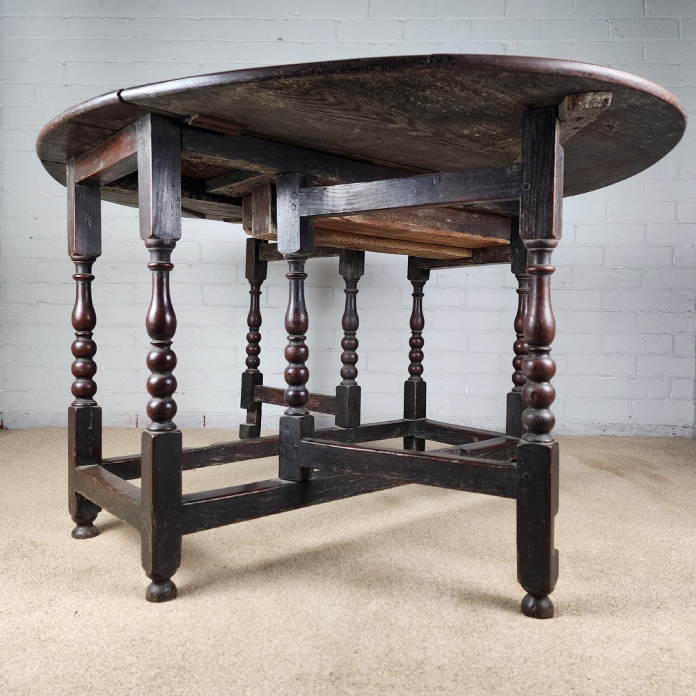 A late seventeenth-century dark oak gateleg dining table with turned legs and two drop leaves extended. View VIII