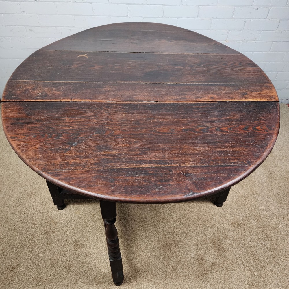 A late seventeenth-century dark oak gateleg dining table with turned legs and two drop leaves extended. View IX