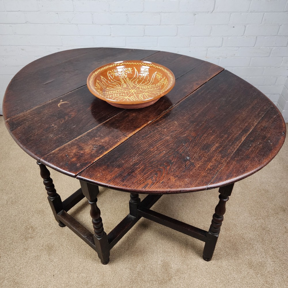 A late seventeenth-century dark oak gateleg dining table with turned legs and two drop leaves extended.