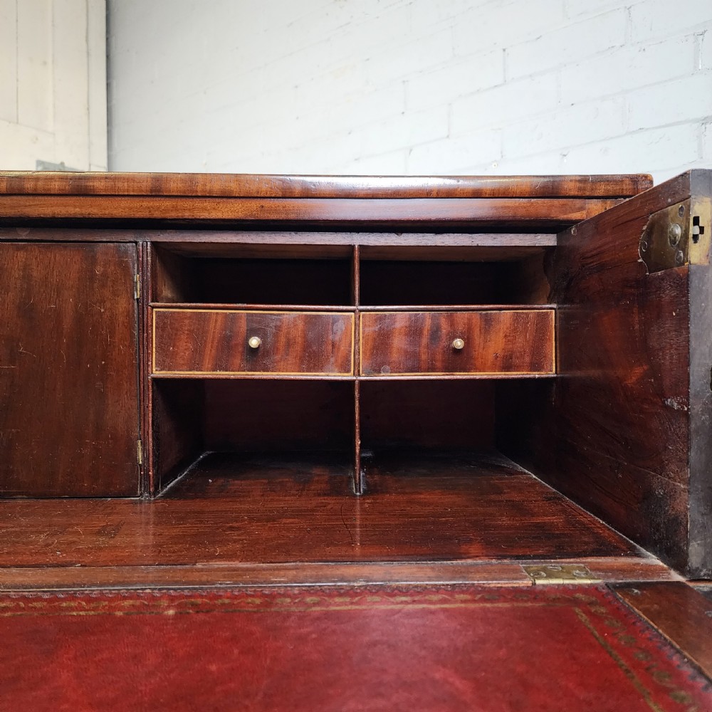 A Georgian mahogany secretaire chest of drawers featuring an open drop-front top section with small fitted drawers and pigeonholes above three lower drawers. View V