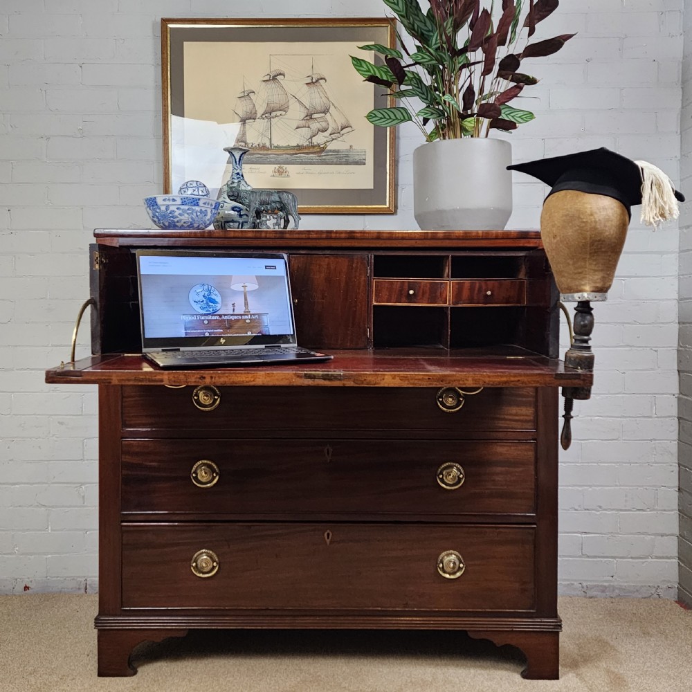 A Georgian mahogany secretaire chest of drawers featuring an open drop-front top section with small fitted drawers and pigeonholes above three lower drawers.