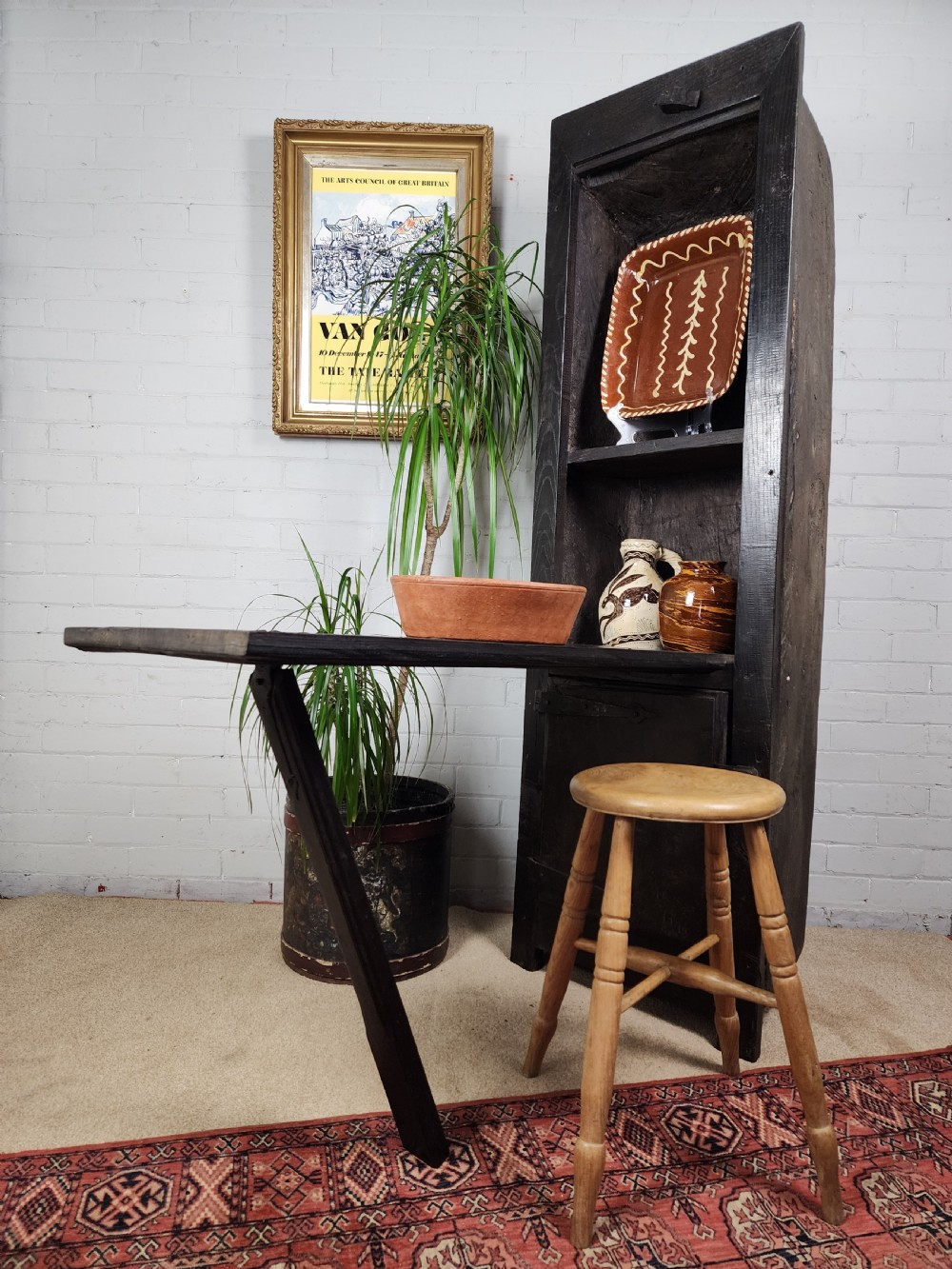 A tall dark oak metamorphic cupboard featuring open shelving, a lower cabinet, and an extended hinged table leaf supported by a angled leg.