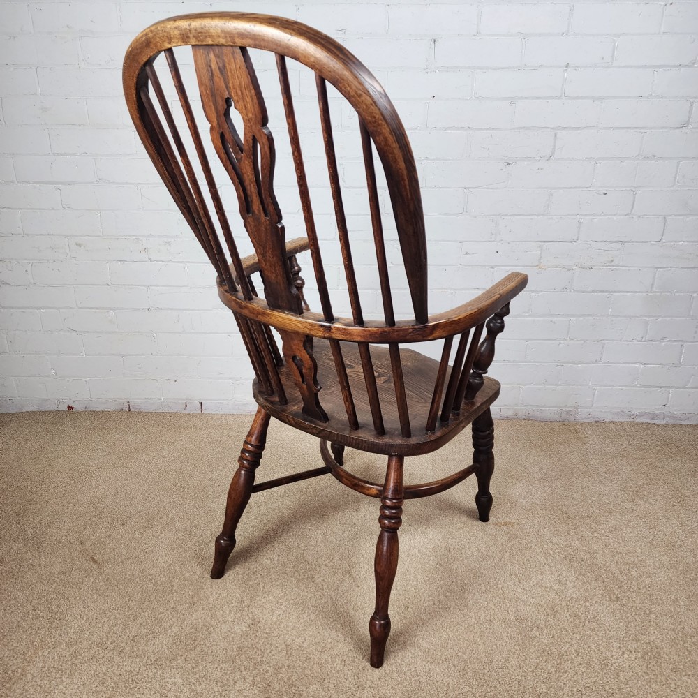 A 19th-century dark wood Windsor armchair featuring a high hoop back, pierced splat, turned legs, and a shaped elm seat. View V