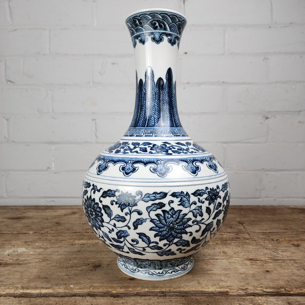 A Chinese blue and white porcelain bottle vase featuring hand-painted floral lotus scrolls and geometric leaf borders. View V