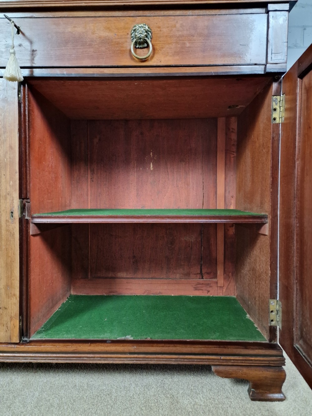 A George IV mahogany bookcase cupboard featuring glazed upper doors with Gothic arch glazing bars above a lower panelled cupboard. View X