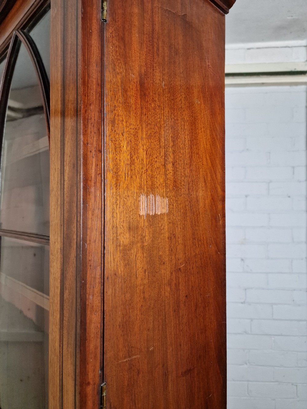 A George IV mahogany bookcase cupboard featuring glazed upper doors with Gothic arch glazing bars above a lower panelled cupboard. View XIII