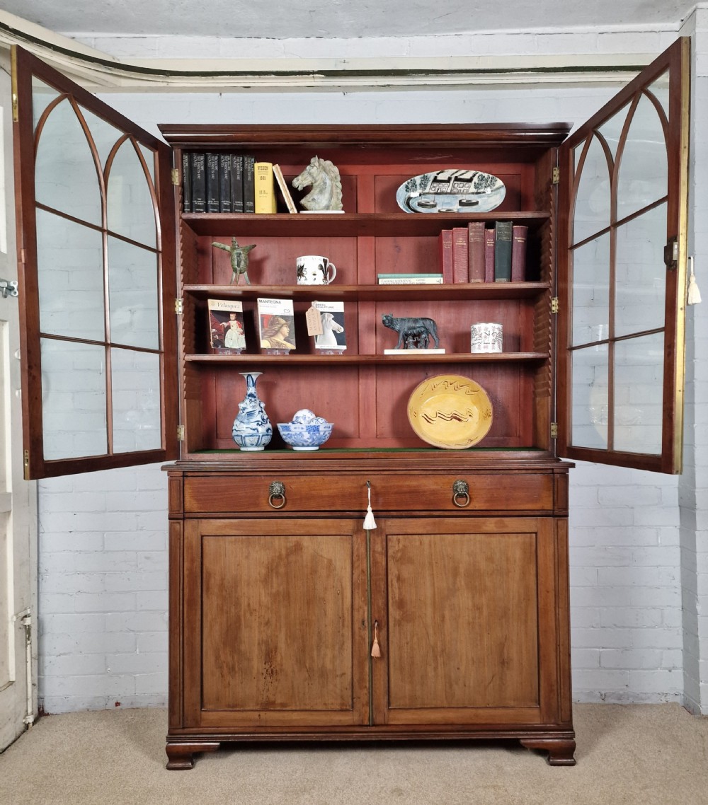 A George IV mahogany bookcase cupboard featuring glazed upper doors with Gothic arch glazing bars above a lower panelled cupboard. View XVIII