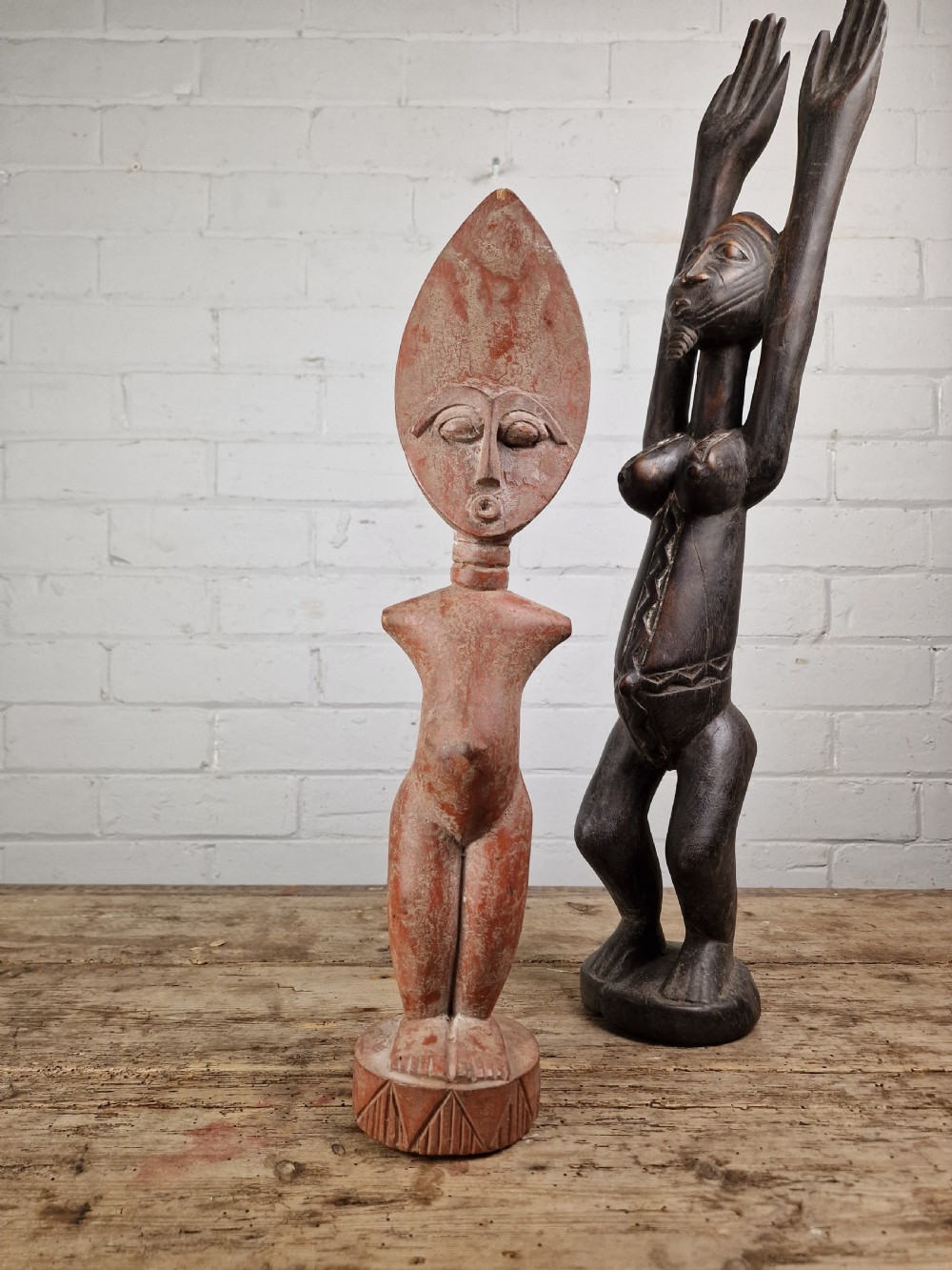 A hand-carved wooden standing Fante figure featuring an elongated crescent head, ringed neck, and a carved circular base in a reddish-brown colour. View II