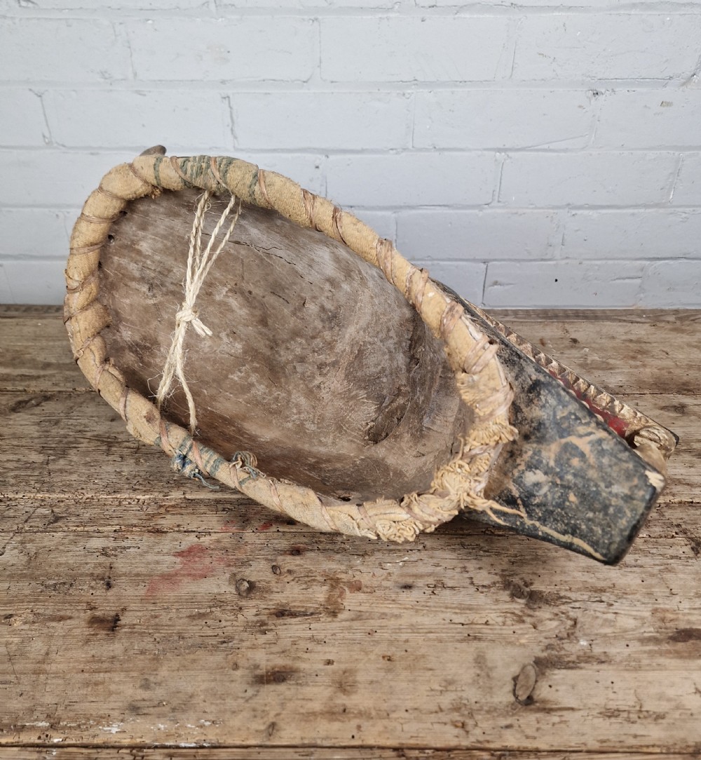 A carved wooden Guro Zamble helmet mask featuring an open-jawed snout with carved white teeth, red painted interior, dark horns, and woven fibre stitching along the base. View X