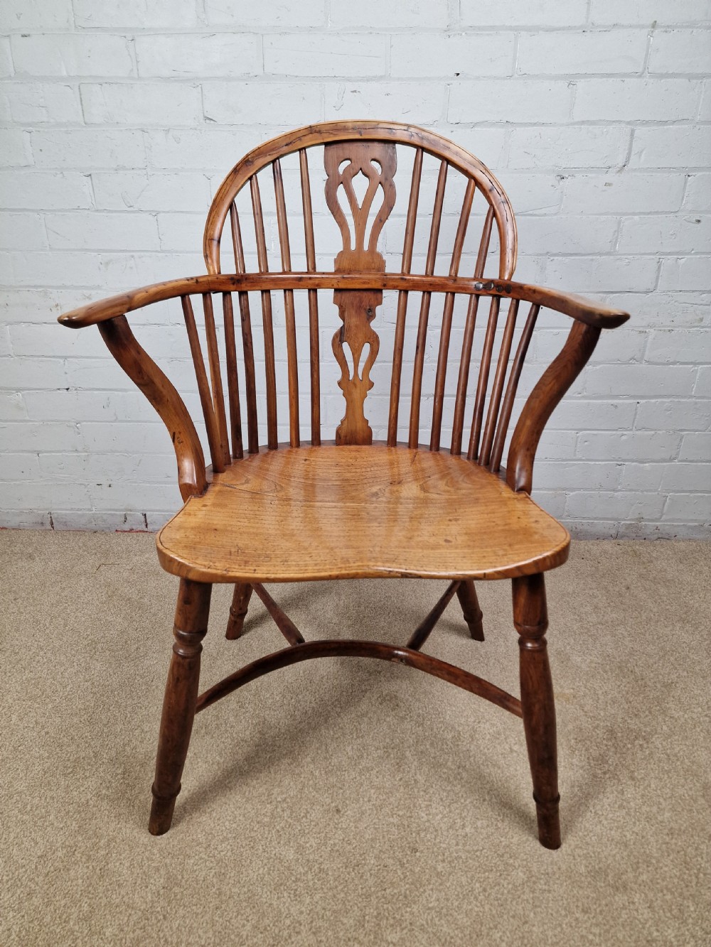 An early nineteenth-century Windsor armchair crafted from yew and elm, featuring a hoop back, pierced central splat, turned legs, and a curved crinoline stretcher. View II